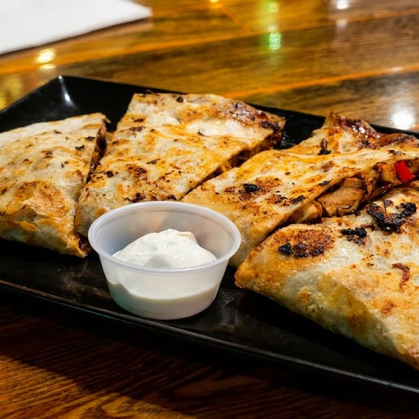 Grilled quesadillas with chicken and red peppers, served with a side of sour cream.
