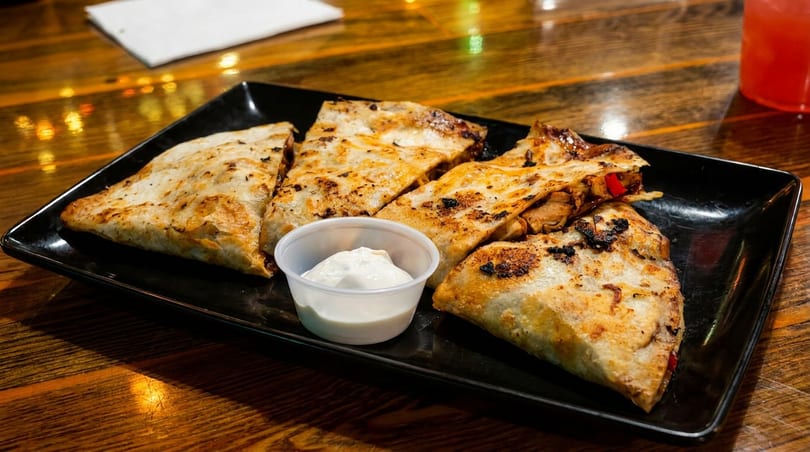 Grilled quesadillas with chicken and red peppers, served with a side of sour cream.